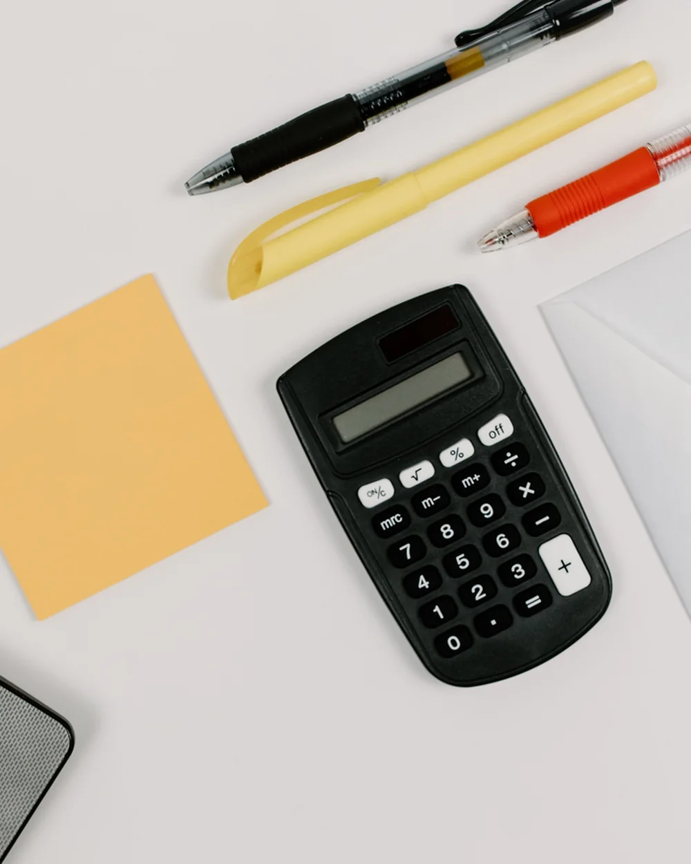 Calculator, notebook, envelopes, and office supplies arranged on a desk