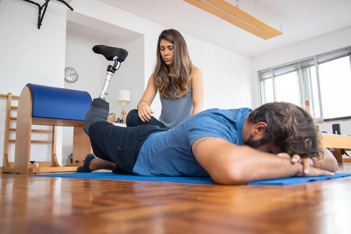 Physical therapist assisting an adult who uses a prosthetic leg