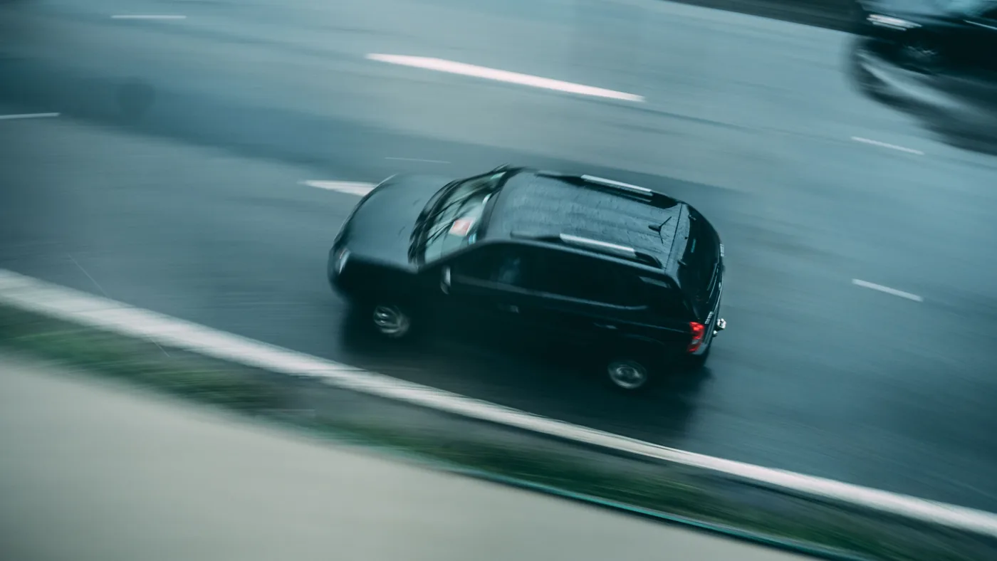 Black SUV moving fast on a wet highway, seen from above with motion blur
