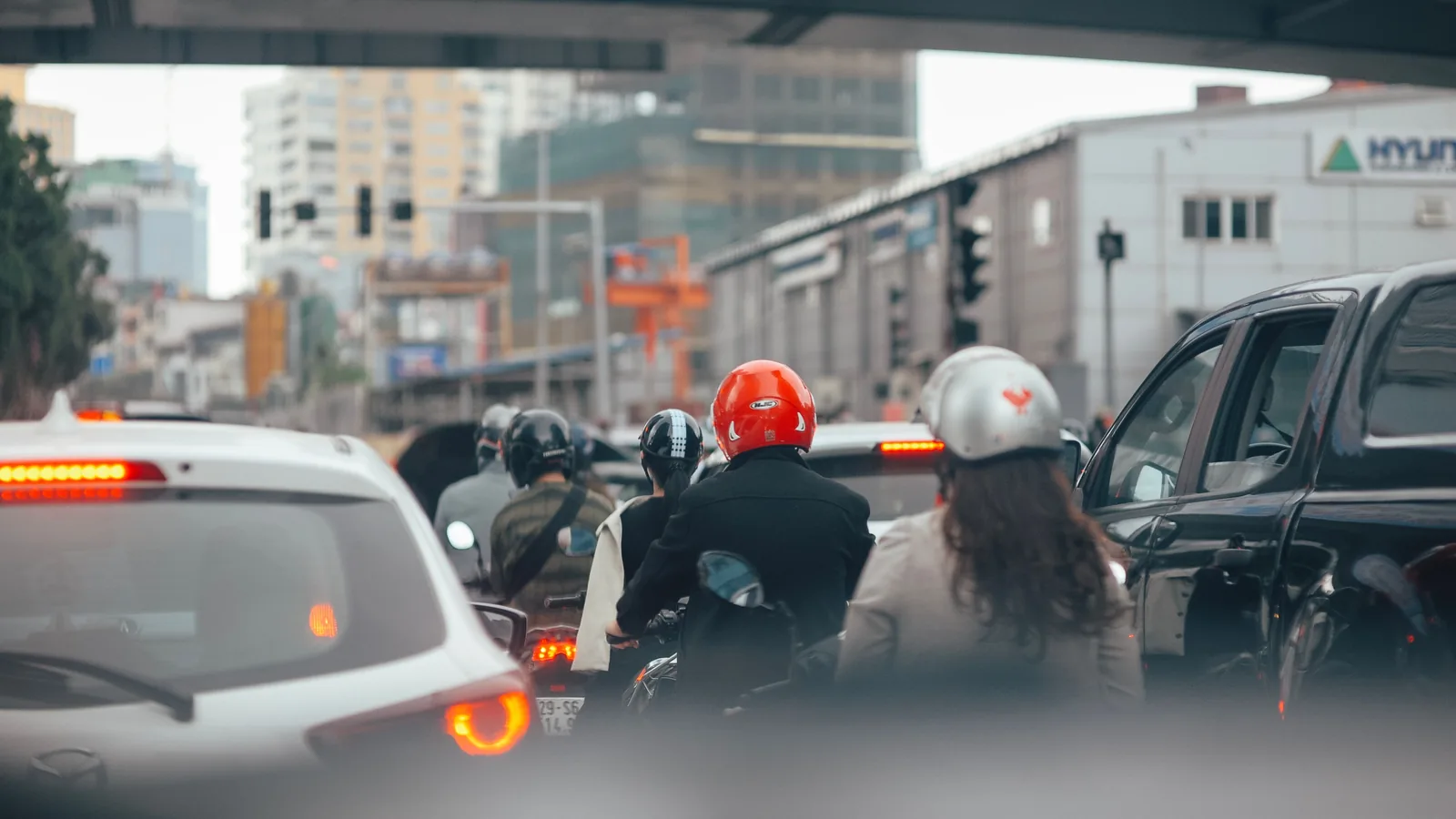 Helmeted motorcyclists and cars waiting in urban traffic
