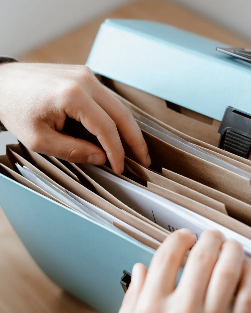 Hands organizing paper records in an accordion file