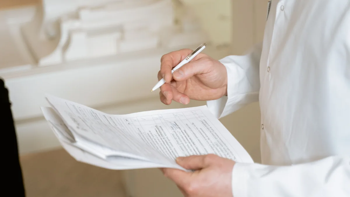 Medical professional reviewing a paper record with a pen