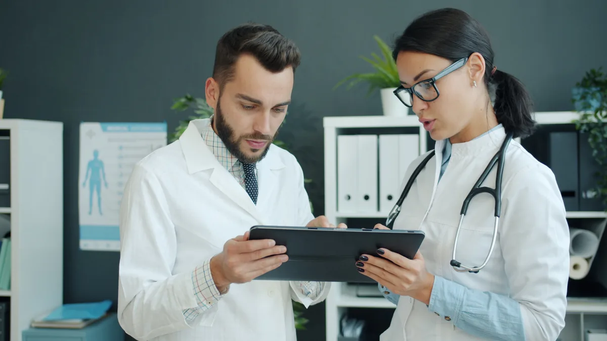 Two medical professionals reviewing information on a tablet