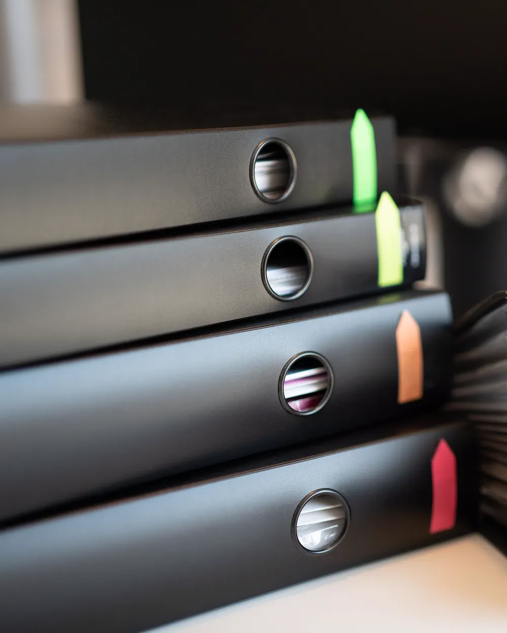 Stacked black document binders with colored index tabs