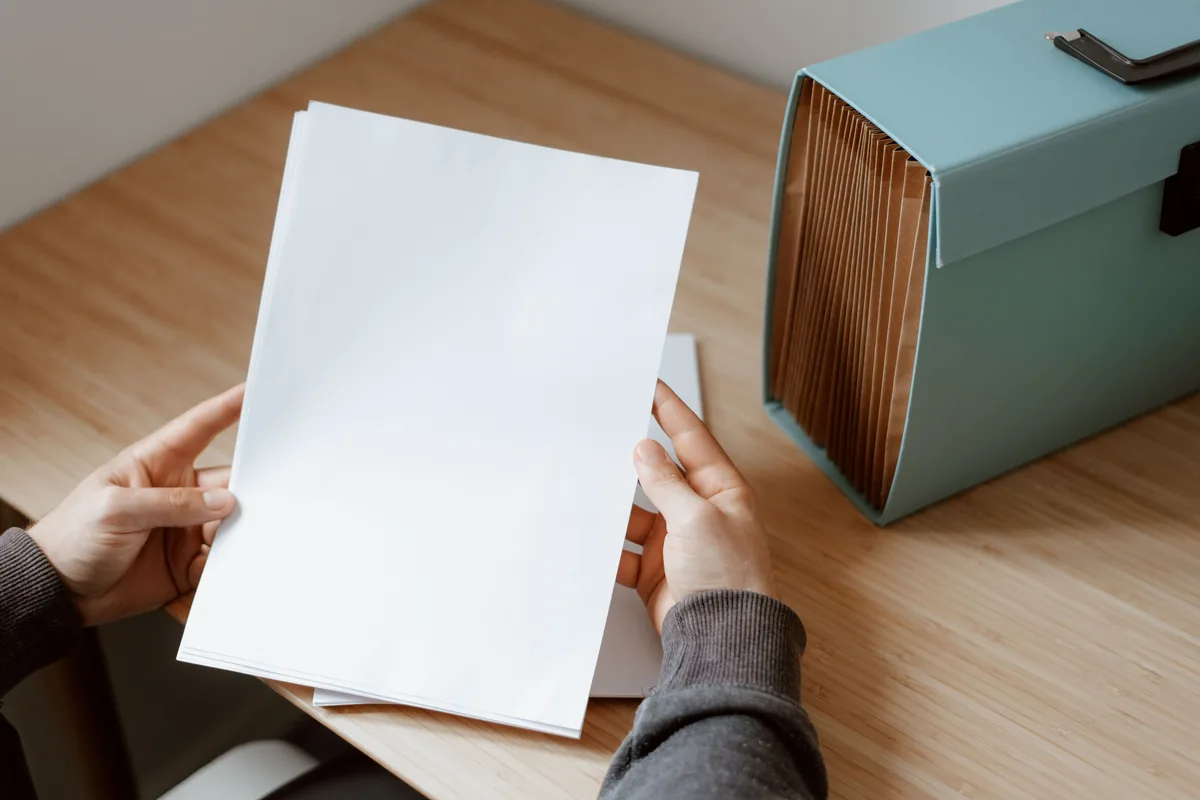Hands holding a blank paper beside a blue file box