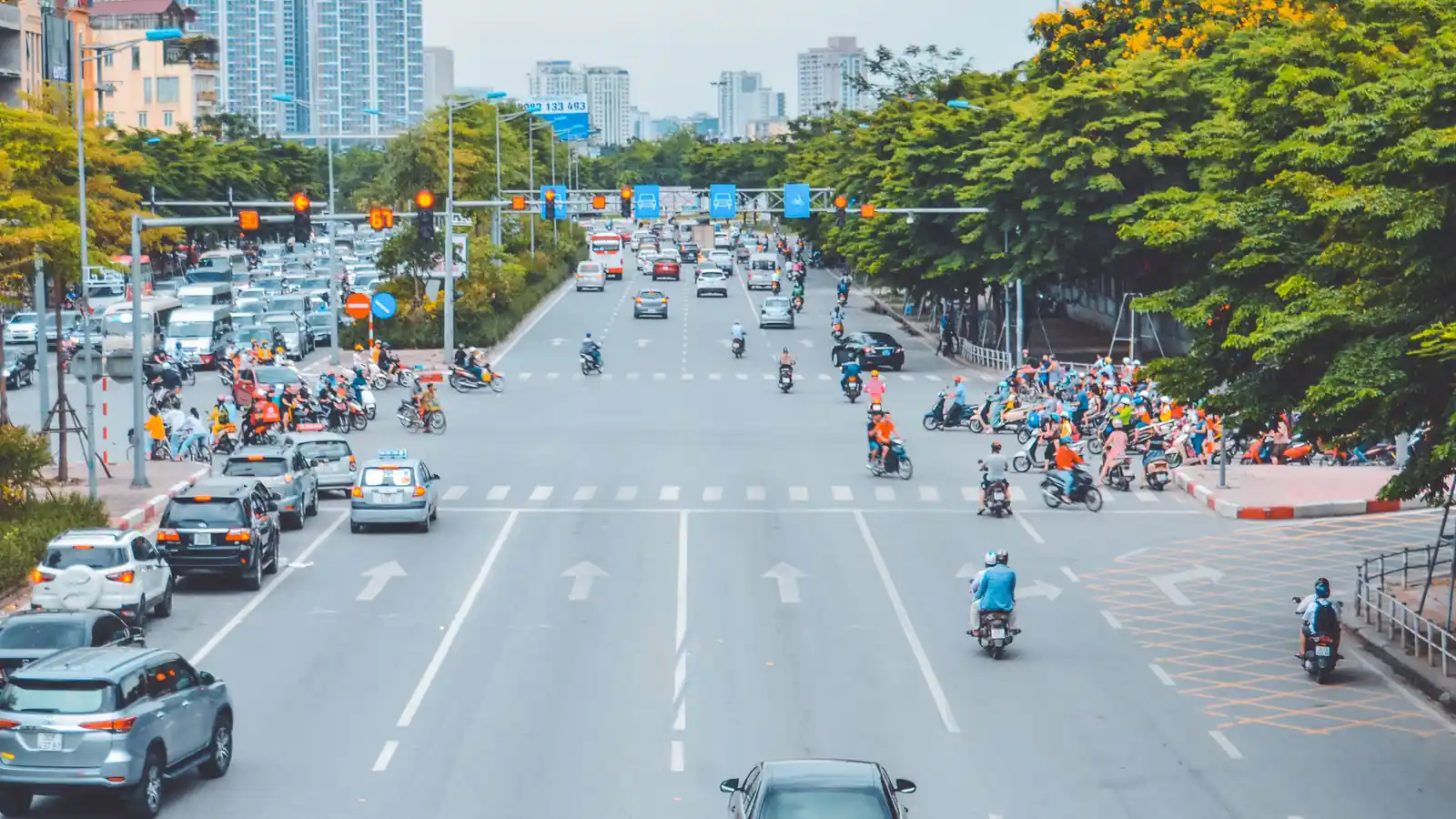 Cars and motorcycles moving through a busy urban intersection