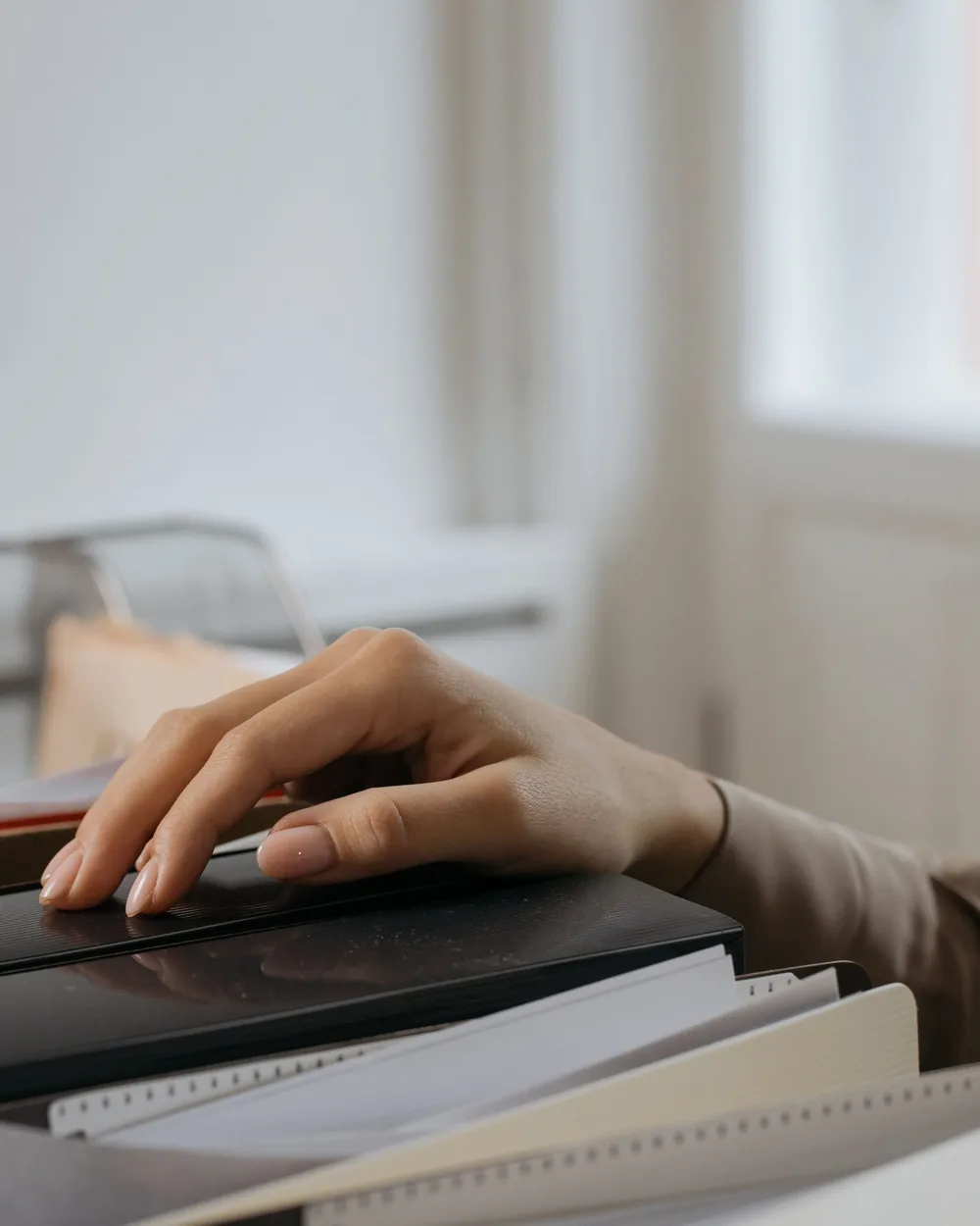 Hand reaching toward labeled office file folders