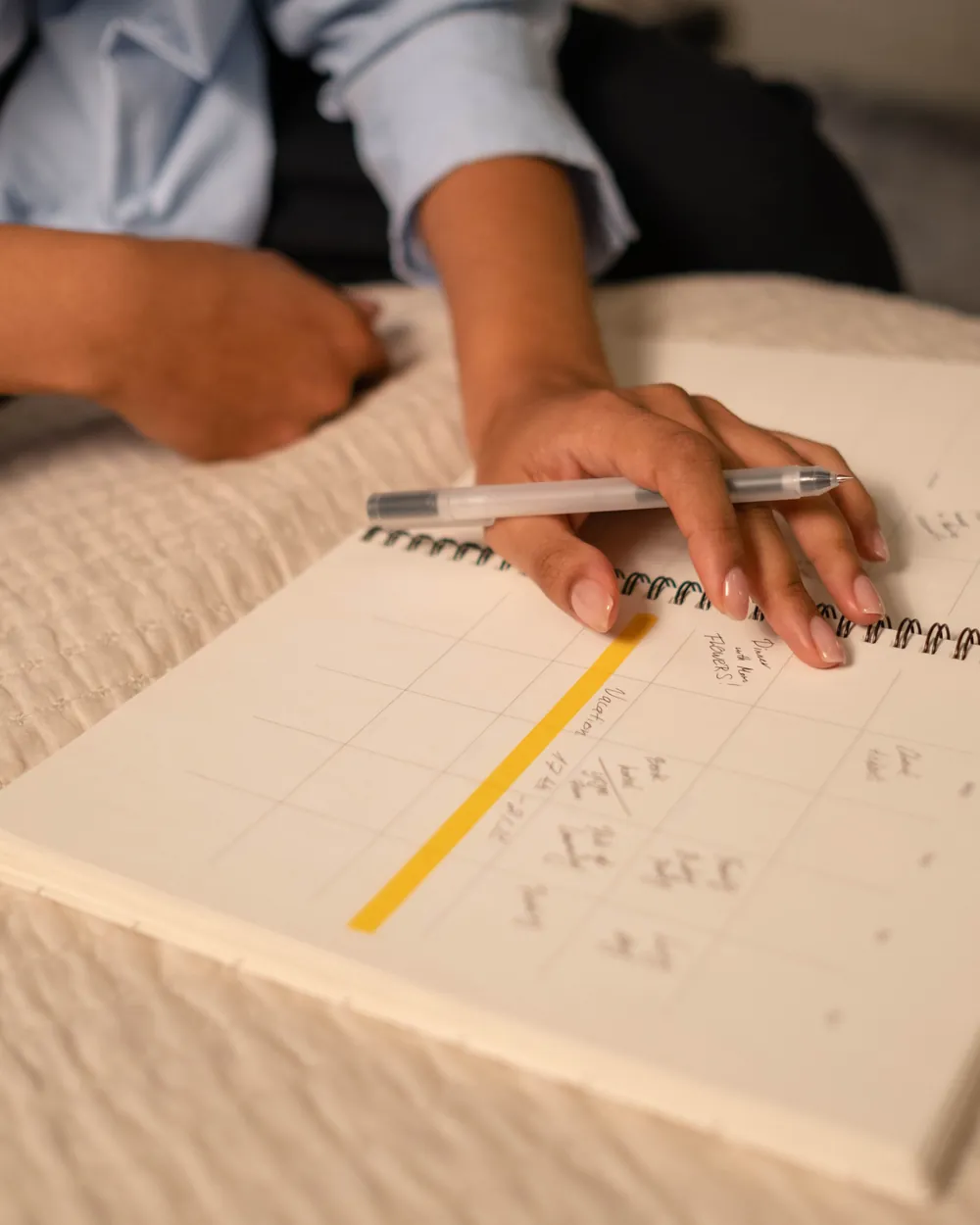 Hands writing in a spiral-bound planner