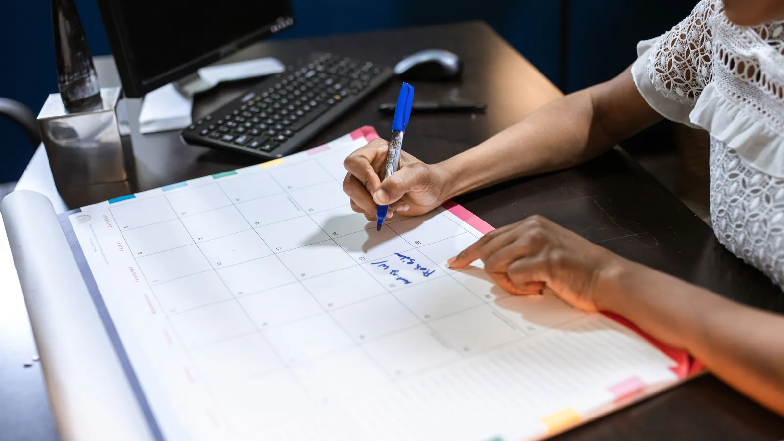 Hands marking dates on a large office calendar