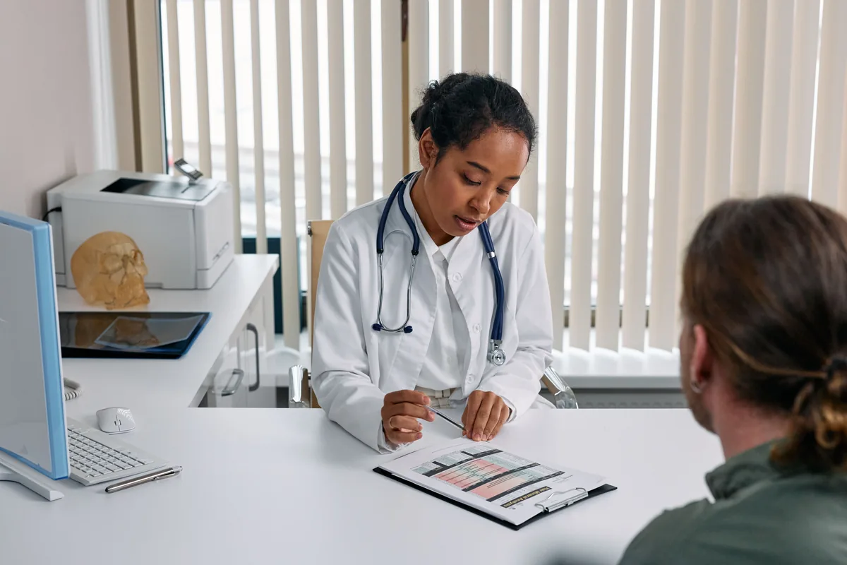 Doctor reviewing a chart with a person seated across a desk