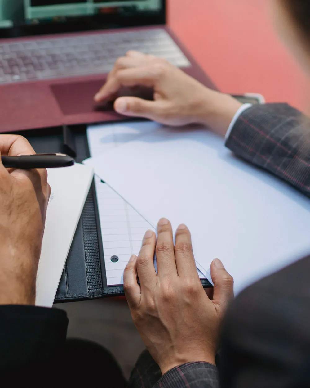 Two professionals reviewing notes beside a laptop