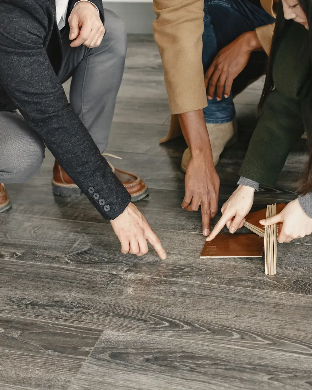 Three people pointing at wood flooring samples