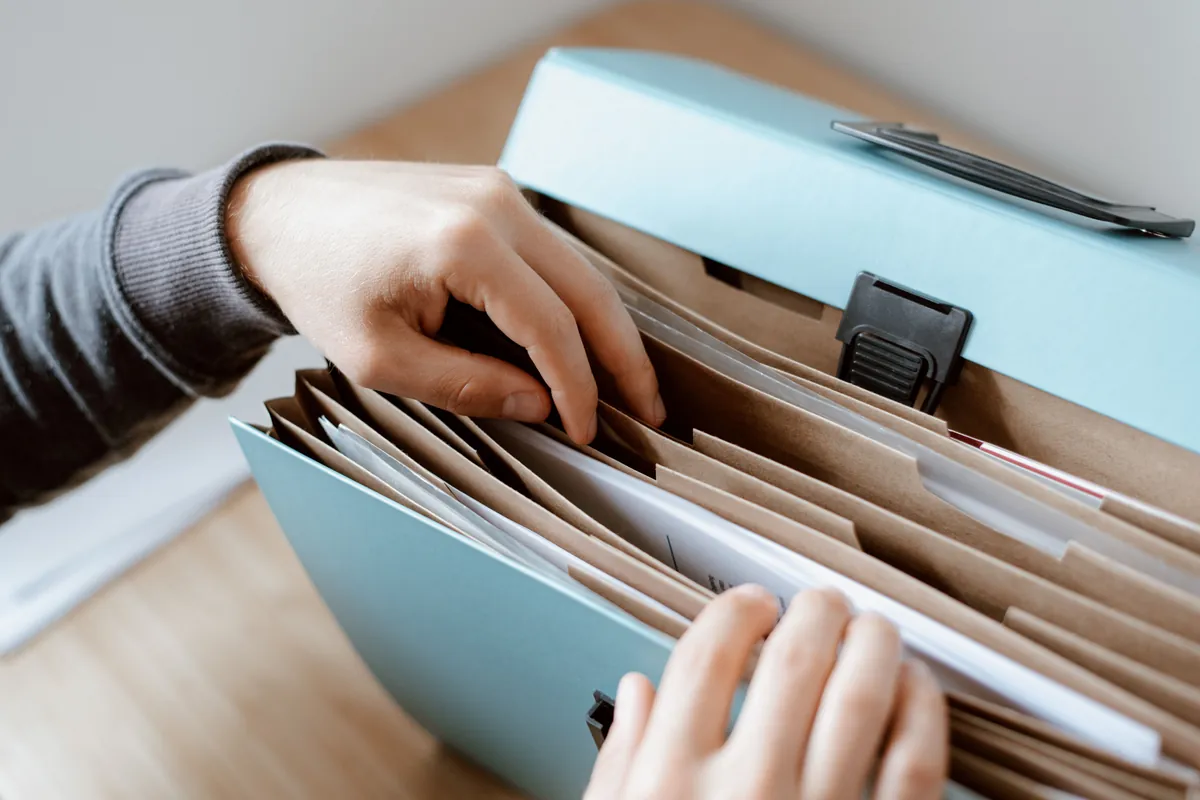 Hands sorting records in an accordion file