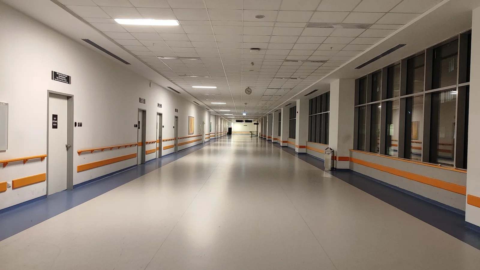 Wide, empty hospital corridor with handrails along both walls
