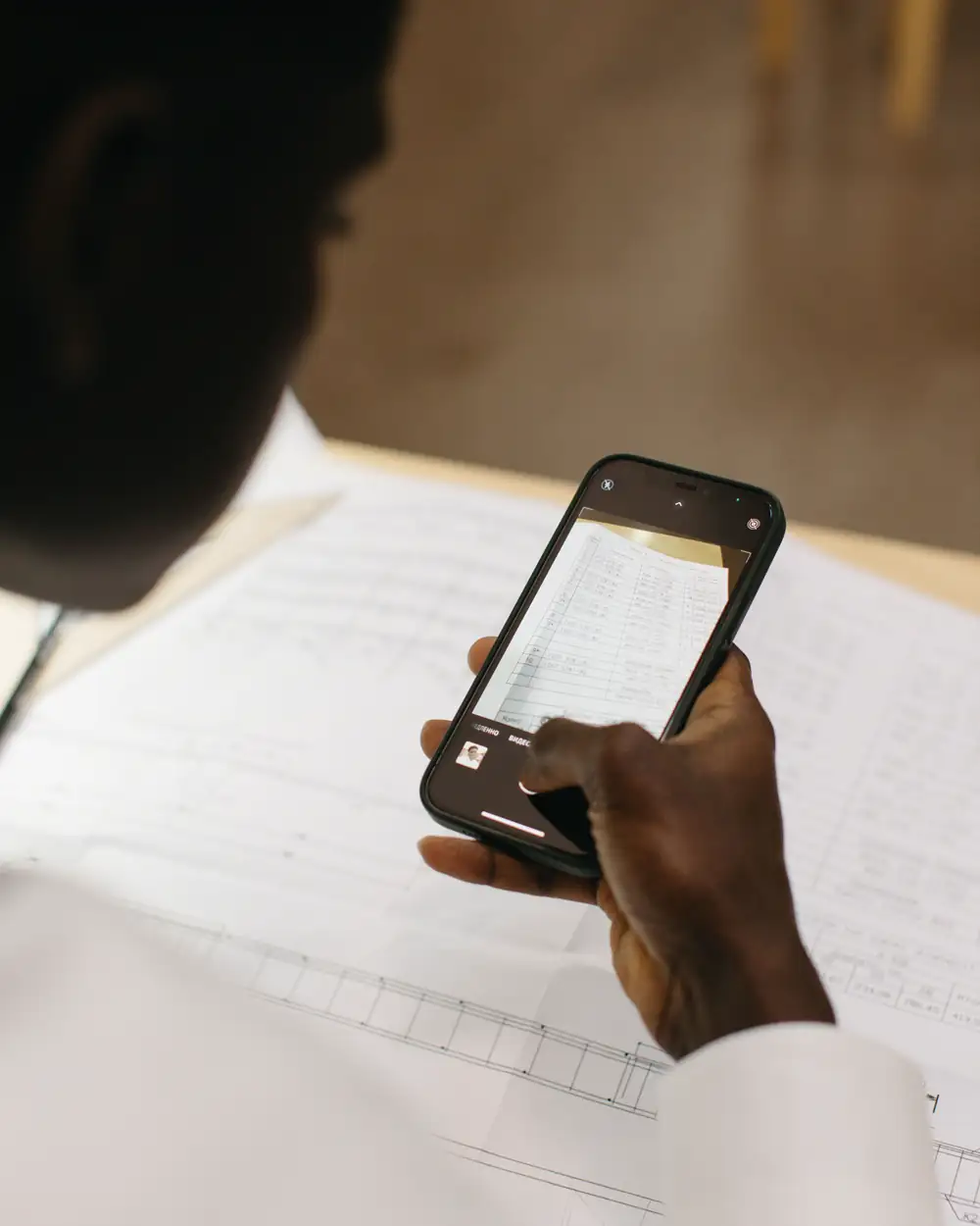 Person using a smartphone to scan a document at a desk