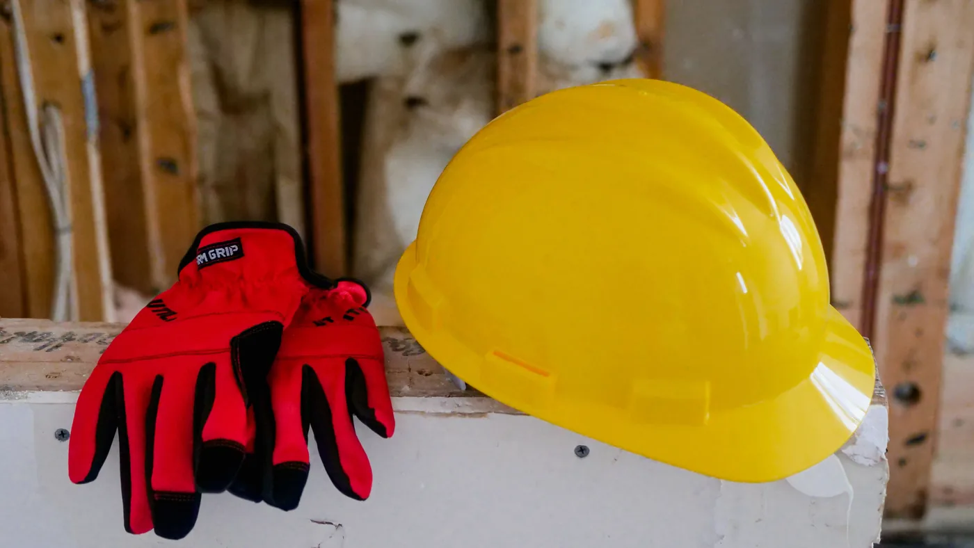 Yellow hard hat and red work gloves resting on a wall at a house construction site