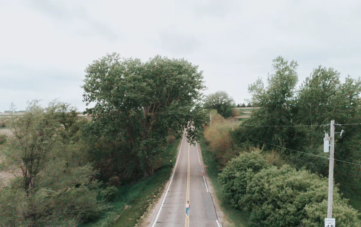 Cyclist riding along a two-lane Nebraska road bordered by trees